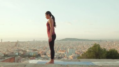 Genç bir kadın gün doğumunda izleme platformunda yoga yapıyor. Amanho mukha svanasana pozu