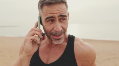 Yakından, spor giyim sektöründe olgun bir adam cep telefonuyla konuşuyor.