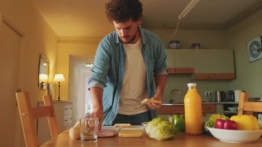 Genç adam mutfakta sandviç pişiriyor.