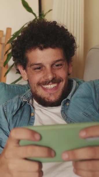 Lächelnder Gamer Spielt Videospiele Mit Handy Auf Sofa Liegend — Stockvideo