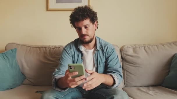Zdenerwowany Mężczyzna Siedzi Kanapie Używając Telefonu Komórkowego — Wideo stockowe