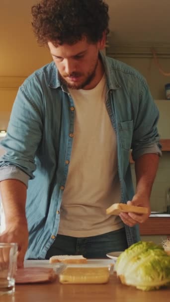 Αγνώριστος Νεαρός Άνδρας Μαγειρεύει Σάντουιτς Στέκεται Στην Κουζίνα — Αρχείο Βίντεο