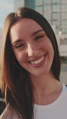 Student with notebooks in her hands looks at the camera and smiles
