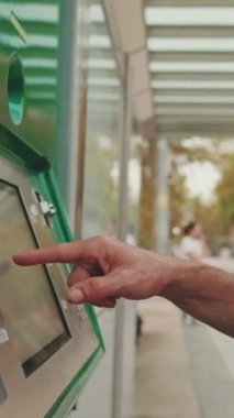 Tanınmayan orta yaşlı bir adamın elleri elektronik terminalde bilet öder.