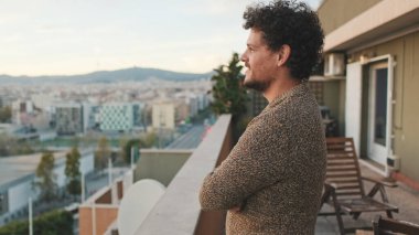 Mutlu adam balkondan şehre bakıyor, güzel manzaranın tadını çıkarıyor.