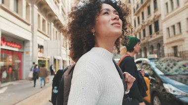 Genç bayan turist yaya geçidi boyunca yürüyor. Sırt çantalı bir kız yaya geçidinde karşıdan karşıya geçiyor.