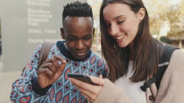 Close-up of a guy and a girl talking to each other and using a mobile phone