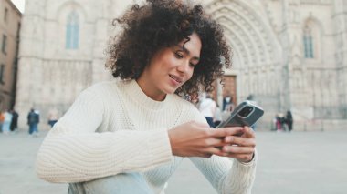 Yaklaş, genç kadın bir cep telefonuna kayıyor. Mutlu kız eski şehir geçmişinde cep telefonu kullanıyor.