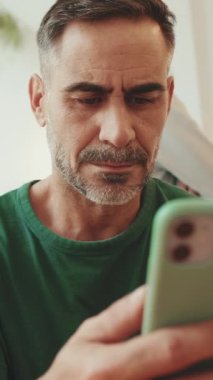 Kafede oturan orta yaşlı bir adam cep telefonu kullanıyor.