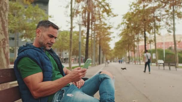 Männlicher Tourist Mittleren Alters Benutzt Handy Während Auf Parkbank Sitzt — Stockvideo