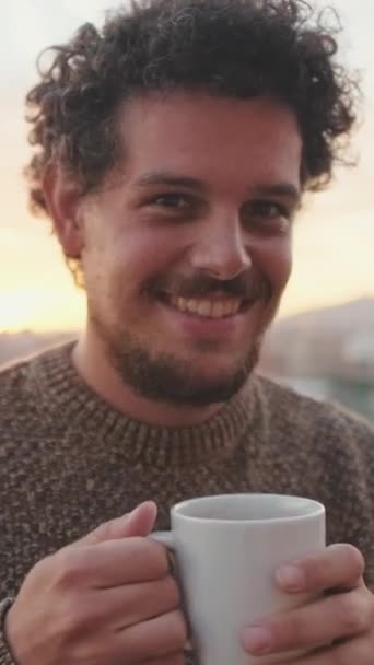Χαμογελαστή Νεαρός Άνδρας Στέκεται Στο Μπαλκόνι Πίνοντας Καφέ Από Κούπα — Αρχείο Βίντεο
