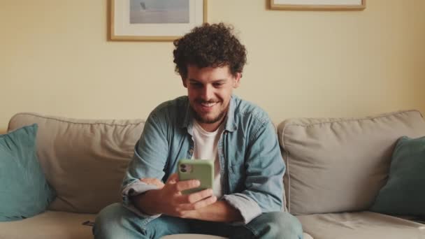 Smiling Man Sitting Sofa Using Mobile Phone — Stock Video