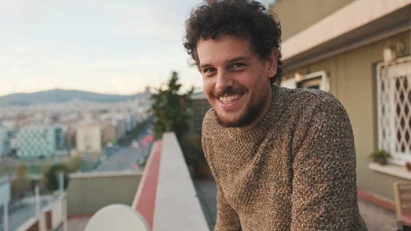 stock image Happy guy looks at the city from the balcony, enjoys the beautiful view