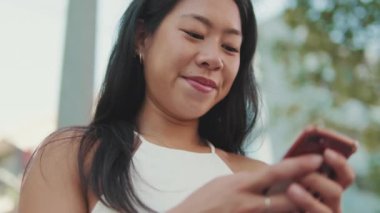 Yaklaş, genç bayan bankta oturuyor ve cep telefonu kullanıyor.