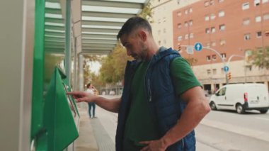 Orta yaşlı bir adam elektronik terminalde bilet ödüyor.