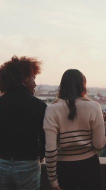 Gençler güzel manzaraya bakar ve balkonda dikilirken konuşurlar.