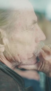 Dikey video, düşünceli yaşlı bir adamın yakın plan portresi tren coupe ile seyahat ederken pencereden dışarı bakıyor, camdan bakıyor.