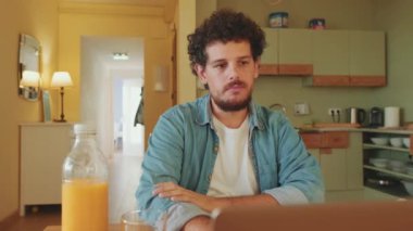 Genç adam mutfakta dizüstü bilgisayar kullanıyor.