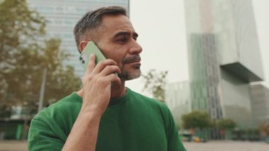 Yakın plan, modern binalarda cep telefonuyla konuşan orta yaşlı adamlar.