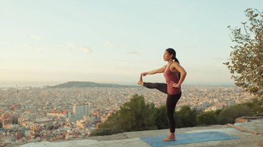 Kız şafak vakti gözetleme noktasında yoga yapıyor.