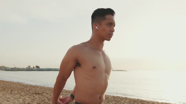 Молодий Атлетичний Чоловік Стоїть Пляжі Робить Розтягування Язів Перед Тренуванням — стокове відео