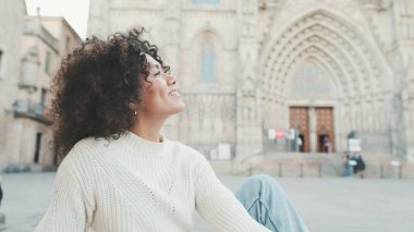 Genç gülümseyen kadın eski şehrin meydanında oturuyor. Turist Barselona meydanında dinleniyor