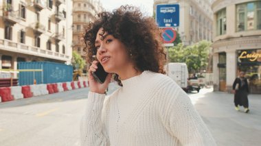 Yaklaş, genç bayan cep telefonuyla konuşuyor. Kız yolun kenarında duruyor, taksi bekliyor ve akıllı telefondan konuşuyor.