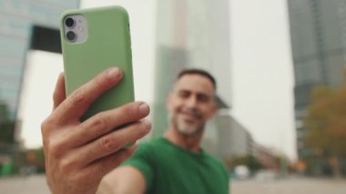 Orta yaşlı bir adamın cep telefonundan selfie çekerken yakın plan fotoğrafı.