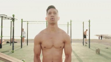 Genç adam dışarıda spor yaparken bir taşı kaldırmaya odaklanmış.