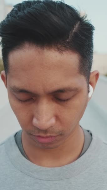 Nahaufnahme Junger Mann Mit Drahtlosen Kopfhörern Steht Auf Einer Brücke — Stockvideo