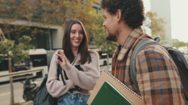 Student couple chatting while standing on the street
