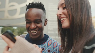 Close-up of a guy and a girl talking to each other and using a mobile phone