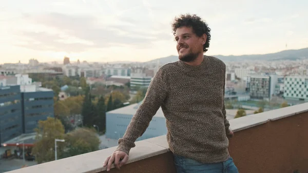 stock image Happy guy looks at the city from the balcony, enjoys the beautiful view