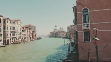 Venedik 'teki kanal, güneşli bir günde turistlerle dolu tekneler ve gondollar kanal boyunca yüzer.