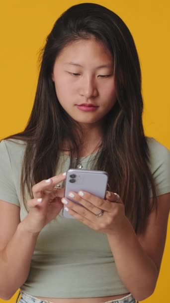Jonge Vrouw Zoek Naar Mobiele Telefoon Kiezen Iets Geïsoleerd Gele — Stockvideo