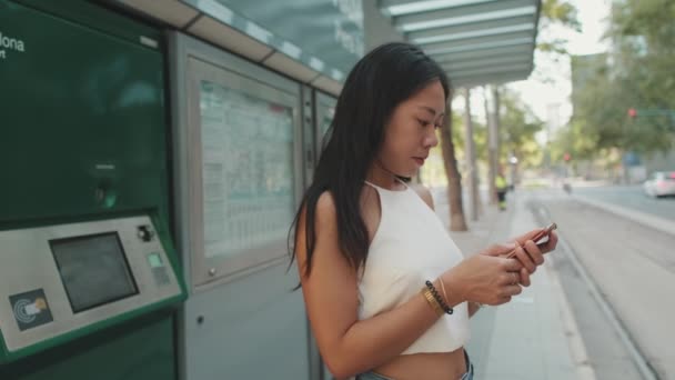 Fiatal Mobiltelefont Használ Miközben Tömegközlekedési Megállóban Áll — Stock videók