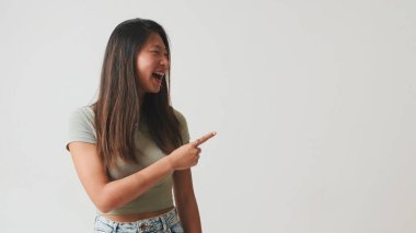 Genç bir kadın gülüyor ve parmaklıyor beyaz arka planda izole edilmiş, stüdyo çekimi