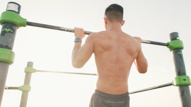 Guy, sporcu ısınma egzersizi yapar, bir yaz günü açık hava spor sahasında durur.