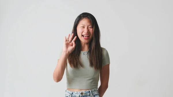 stock image Laughing girl in gray top isolated on white background waving greeting gesture welcomes someone, says hello