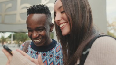 Close-up of a guy and a girl talking to each other and using a mobile phone