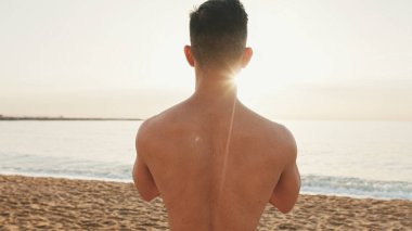 Guy, plajda duran kulaklıklı sporcu yaz günü solunum egzersizi yapar.