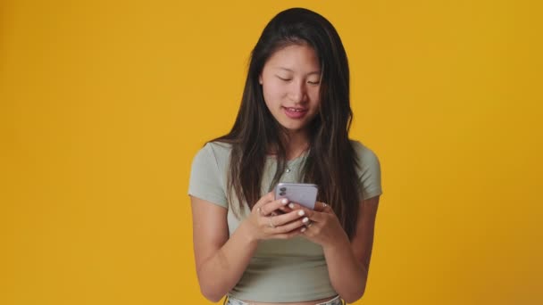 Leende Ung Kvinna Som Använder Mobiltelefon Isolerad Över Vit Bakgrund — Stockvideo