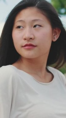 Şehir parkındaki bankta oturmuş etrafa bakan genç bir kadın.