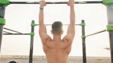 Guy, sporcu ısınma egzersizi yapar, bir yaz günü açık hava spor sahasında durur.