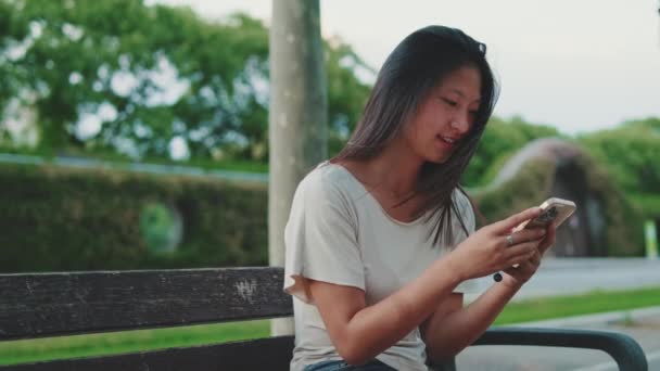 Mujer Joven Usando Teléfono Móvil Mientras Está Sentado Banco Afuera — Vídeos de Stock