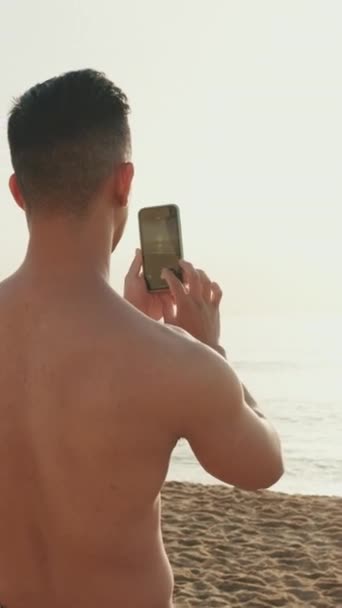 Joven Atlético Parado Playa Filmando Video Teléfono Móvil — Vídeos de Stock