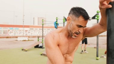 Orta yaşlı kaslı adam dışarıda idmandan sonra dinleniyor.