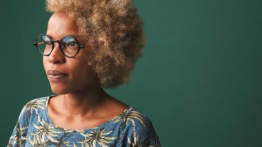 Gözlüklü, mavi tişörtlü, yeşil-mavi arka planda izole edilmiş bir kızın yakın çekimi.