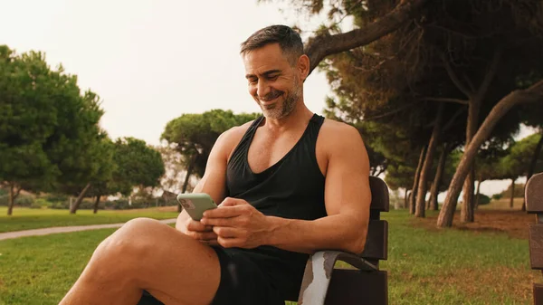Sonriente Hombre Musculoso Mediana Edad Ropa Deportiva Usando Teléfono Móvil — Foto de Stock