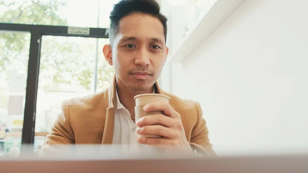 Mladý Podnikatel Nosí Béžové Apartmá Sedí Stolu Notebookem Pije Kávu — Stock fotografie